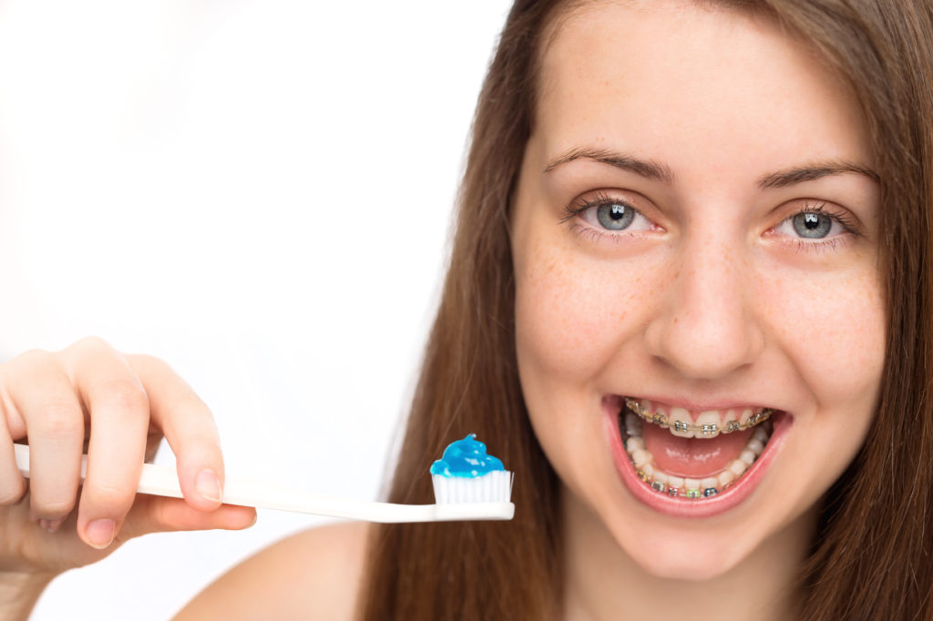 Smiling girl with braces holding toothbrush morning hygiene isolated