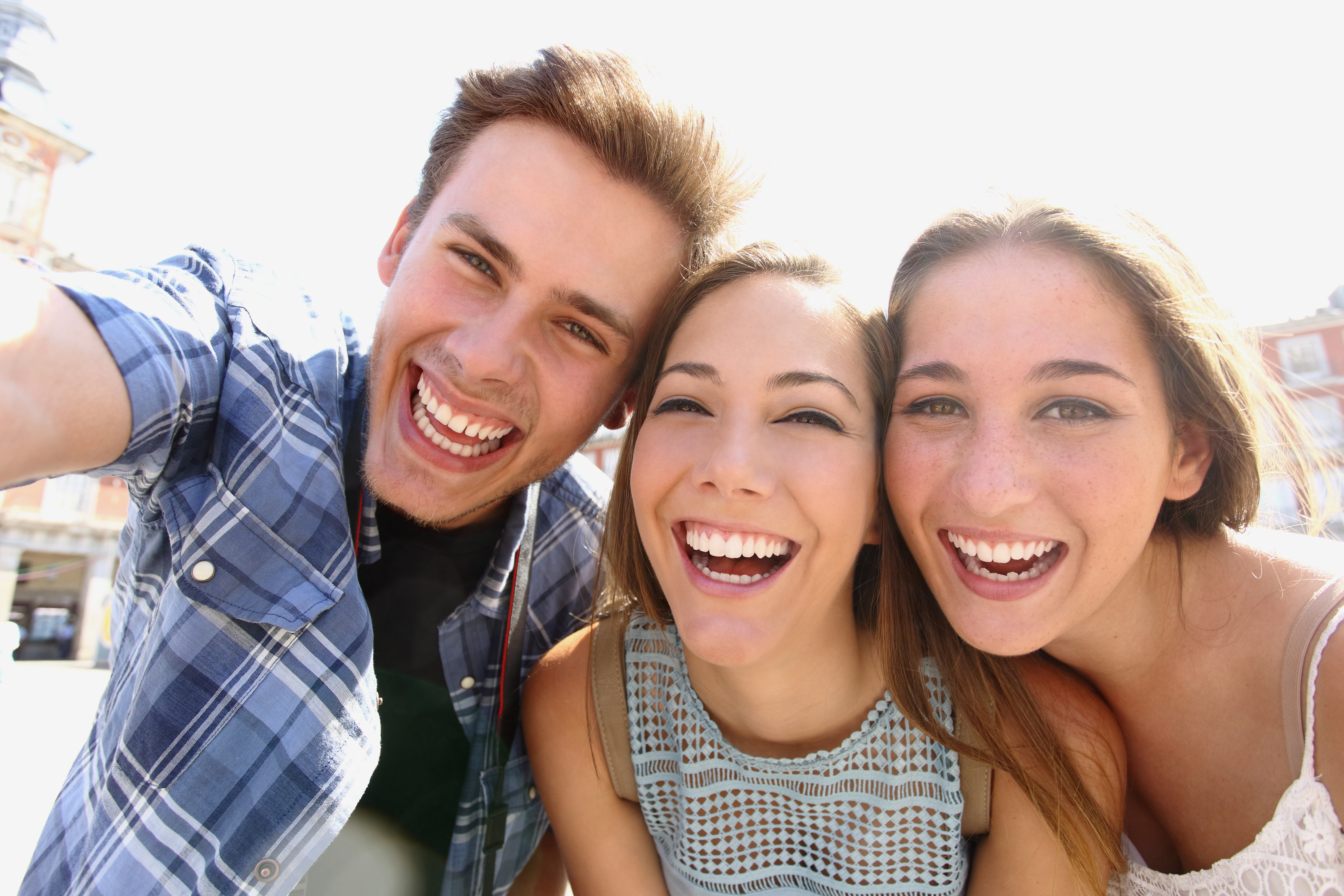 Group of happy teen friends laughing and taking a selfie in the street
